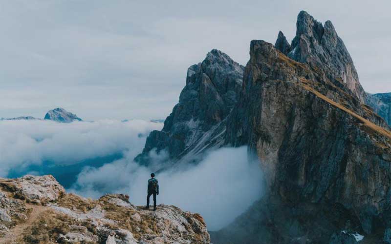 A hiker is standing in front of mountains