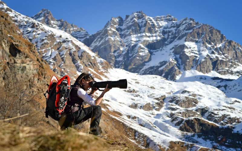 Hiker is taking photo using a telephoto